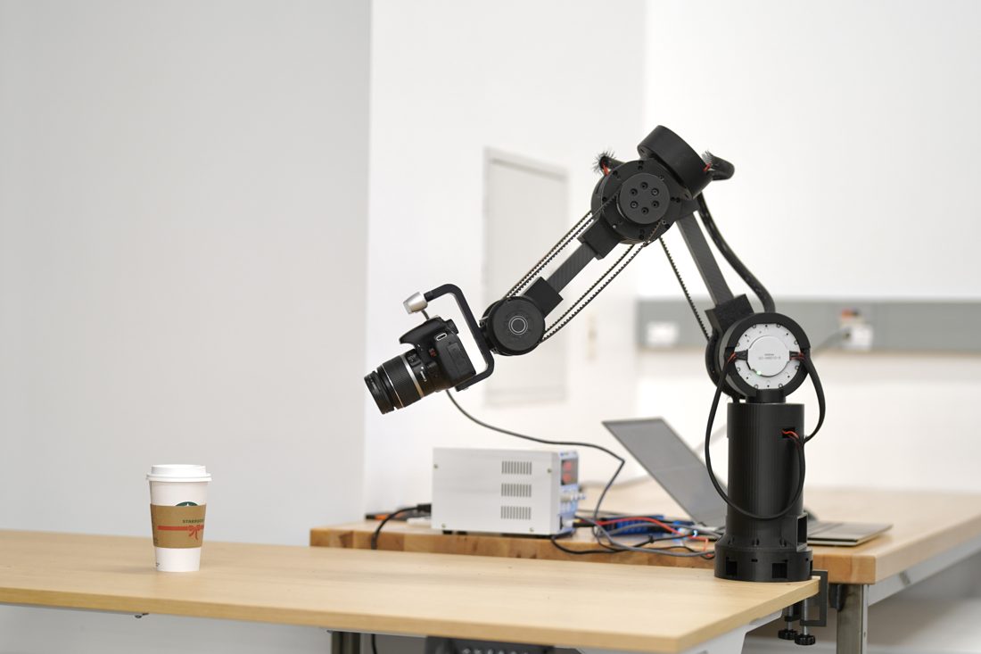 The cinema robot arm on a desk, holding a camera